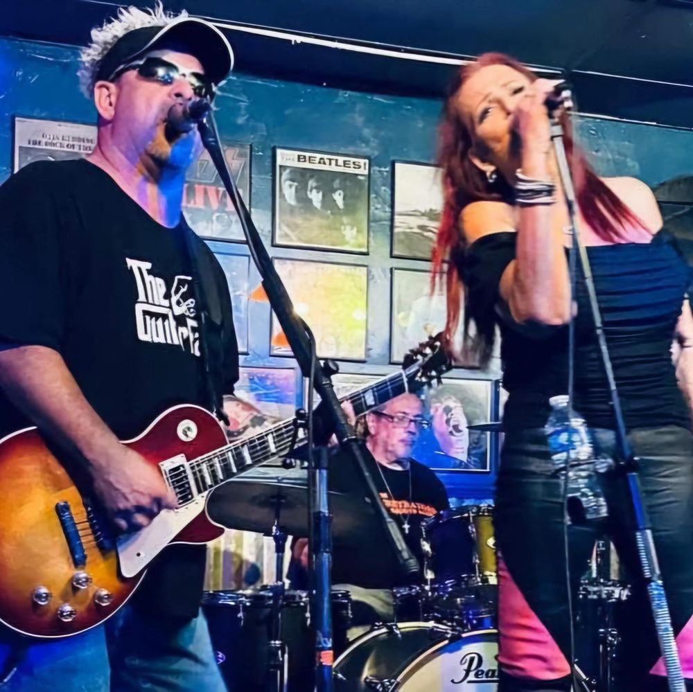 The Penetrators Groove Band singers and guitarist performing on stage