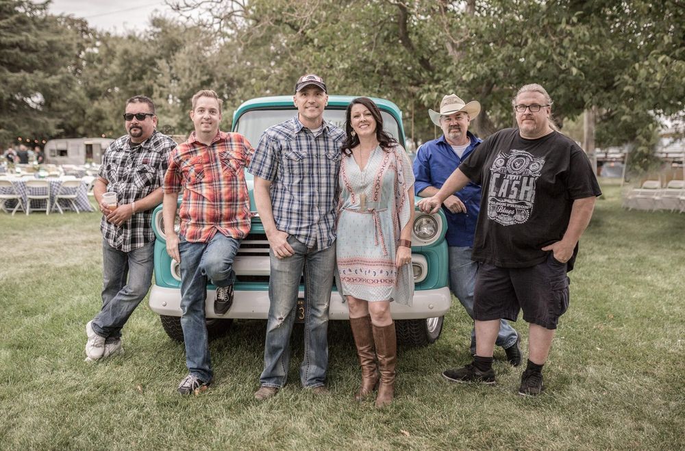 Whiskey Kiss band members posing with a vintage pickup truck