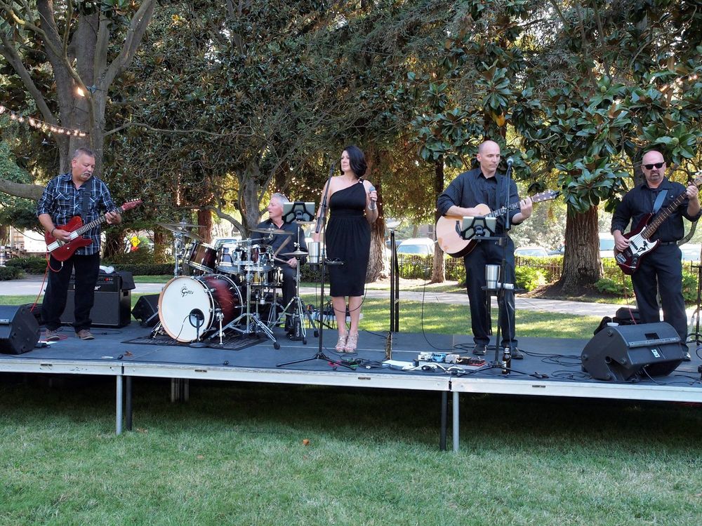 Whiskey Kiss playing an outdoor stage under the trees